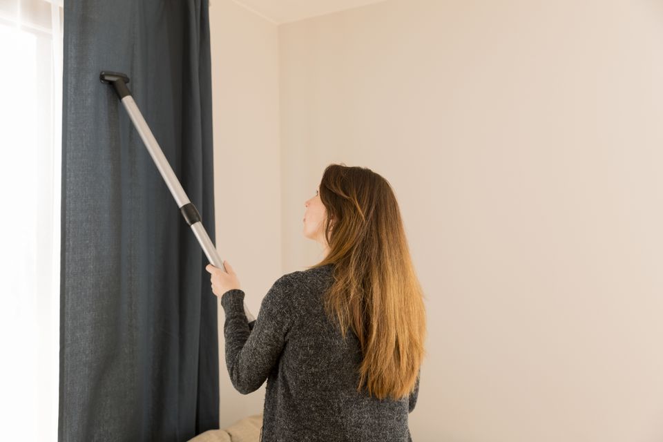mulher limpando cortina com aspirador