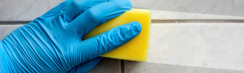 Cleaning sponge held in hand while cleaning bathroom with french lettering nettoyage